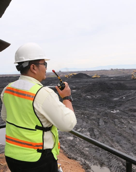 Ingeniero minero con casco blanco comunicandose por intercomunicador, realizando trabajos de seguridad y salud en el trabajo en minería